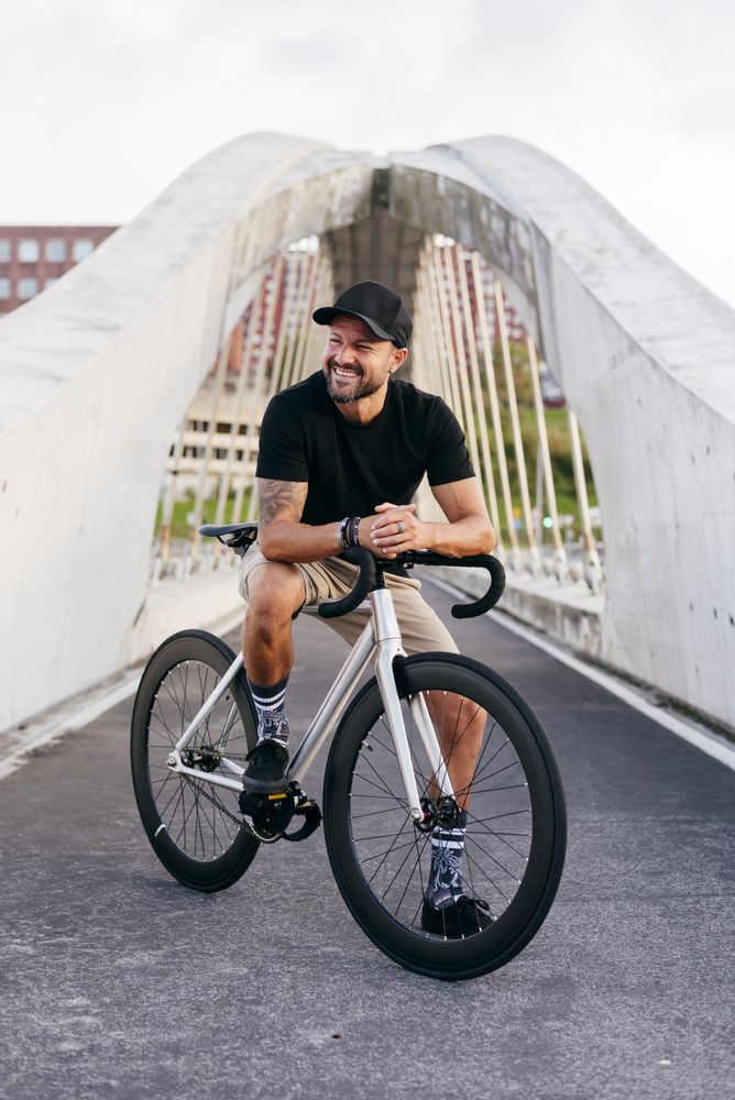 Cheerful man with bicycle standing on footbridge