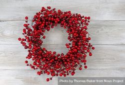 Red berry holiday wreath on old white wooden boards 0PYee5