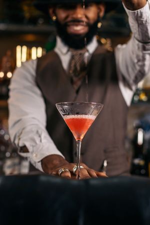 Black bartender preparing a cocktail in a traditional cocktail bar