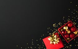 Festive red and gold present with holiday decorations and glitter on dark background