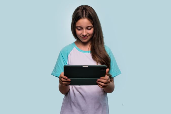 Girl focused on using tablet, possibly for gaming or studying.