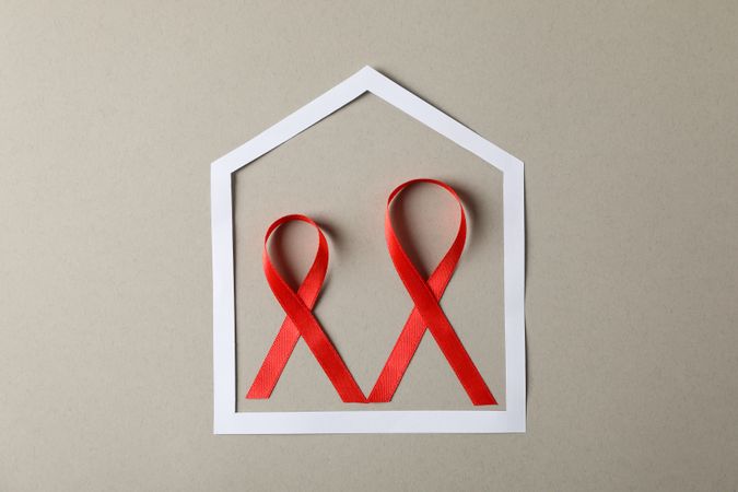 Awareness red ribbons in frame on grey cardboard background, copy space