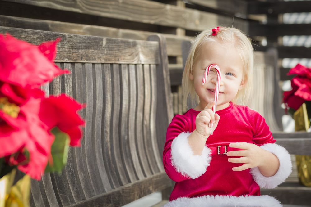 Adorable Little Girl Sitting On Bench with Her Candy Cane