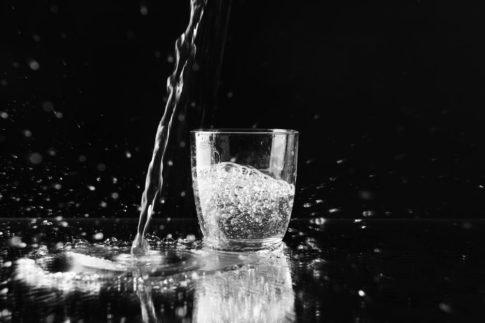 Fresh bubbly water being poured onto table with glass