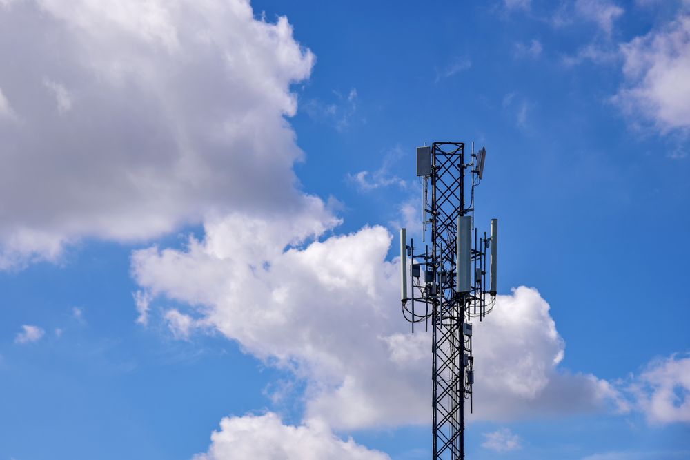 Cell Tower Against a Clear Sky With Clouds in the Background