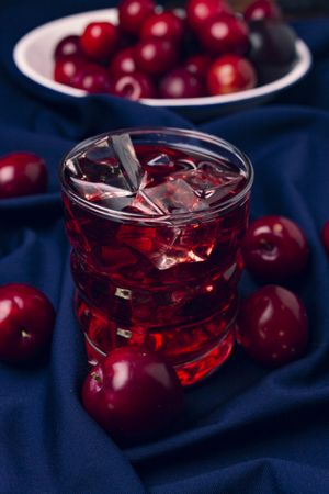 Red beverage near fresh fruits on cloth