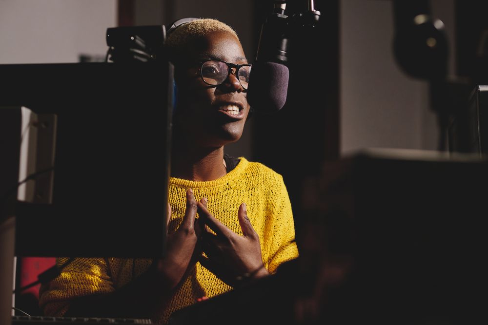 Black woman speaking into microphone in recording studio