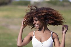 Female pictured outside in park playing with her curly hair
