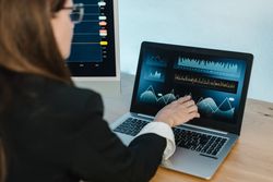 Woman pointing at laptop with financial charts