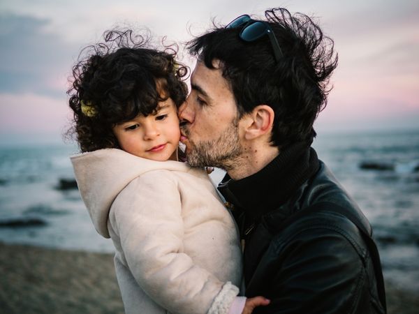 father holding little daughter at the beach