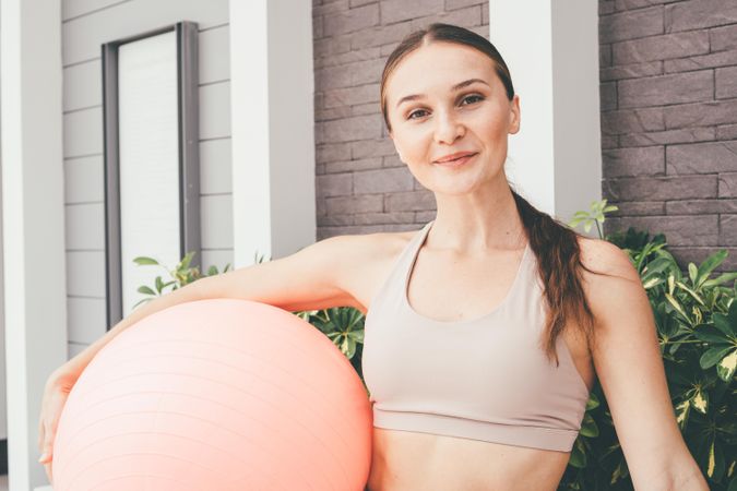 Woman in sports bra holding fitness ball