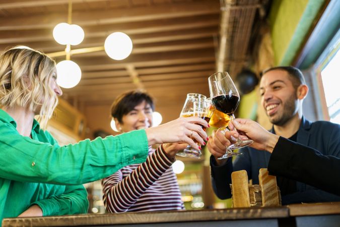 Group of friends clinking beer and wine in bar