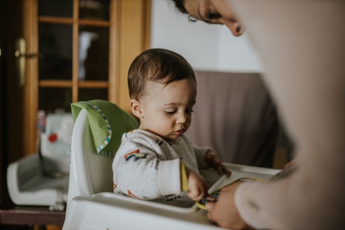 Mother leaning down to her son in a high chair