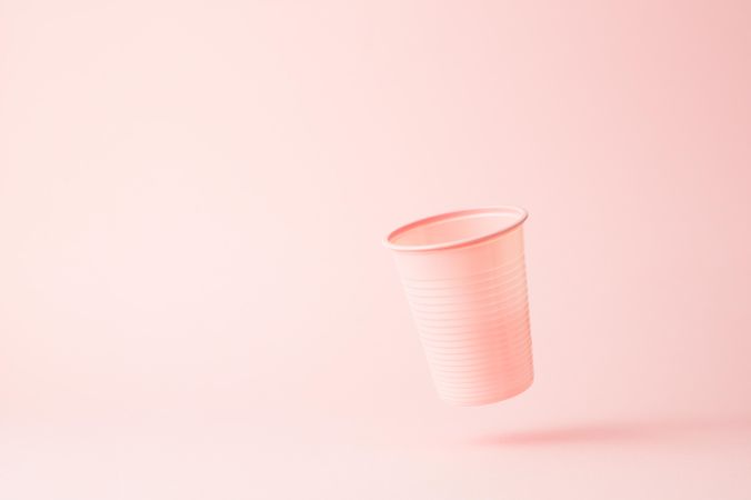Falling pink disposable cup on pink background