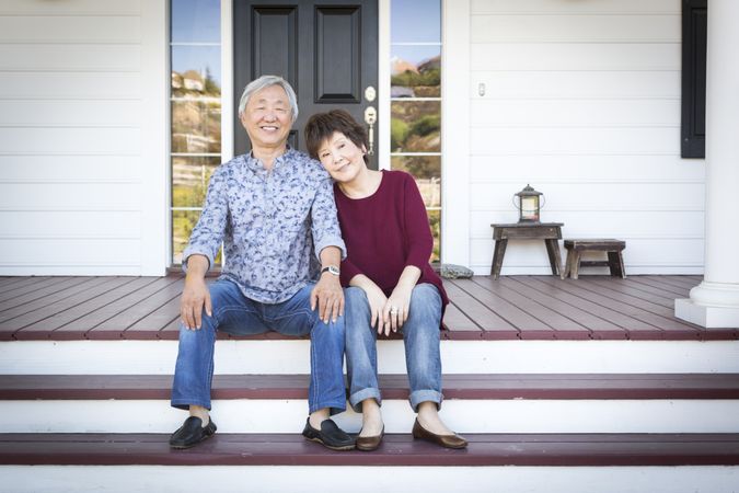 Mature Chinese Couple Sitting on Front Steps of Their House