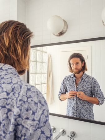 Handsome male checking hairstyle in mirror reflection