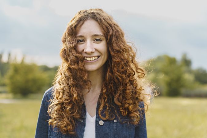 Spontaneous redhead woman smiling looking at the camera outdoors in the countryside