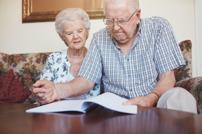 Indoor shot of older couple at home reading paperwork together