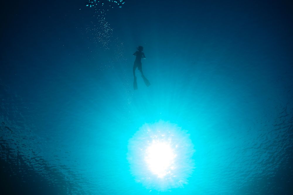 Unrecognizable boy diving in blue sea