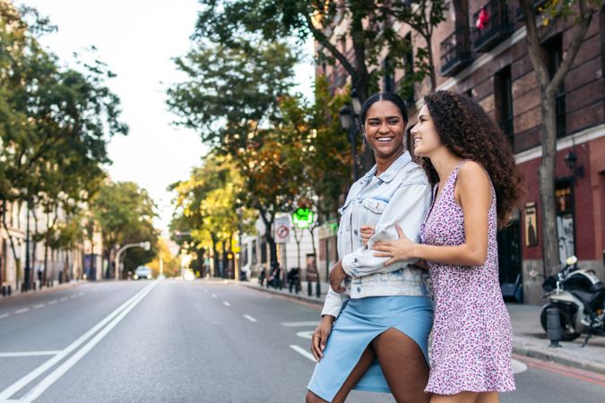 Two Latina women crossing the pedestrian crossing in the city.