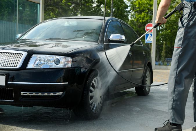 A man washes a car in a manual car wash. Clear car