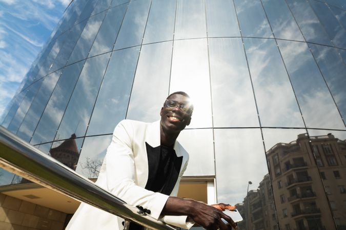 Content Black businessman with smartphone on city street