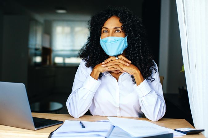 Thoughtful woman wearing a facemask working on documents