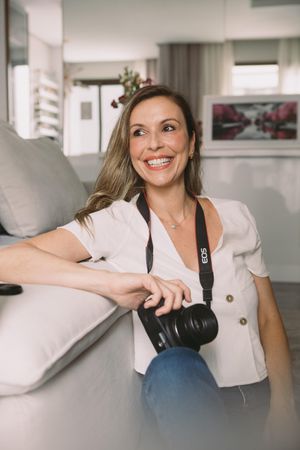 Smiling woman in light shirt holding camera