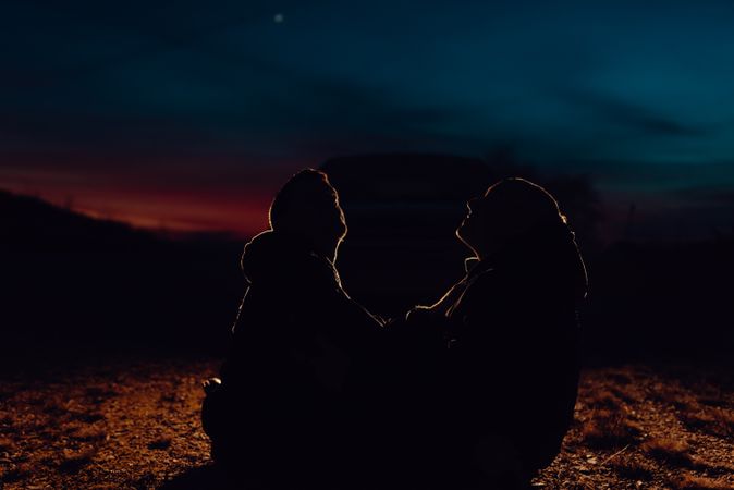 Men hugging and sitting on ground on field at night