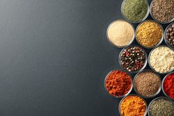 Rows of bowls of spices on dark table, copy space