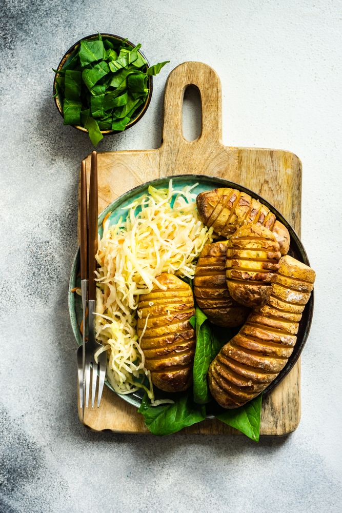 Baked potato, spinach and cabbage salad on marble counter with copy space