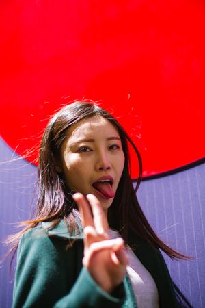 Asian woman showing tongue and V sign