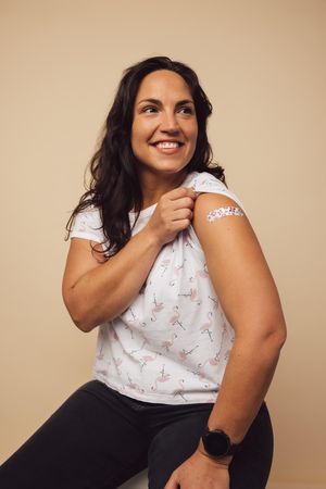 Female holding up her sleeve and showing her arm after getting a vaccine shot