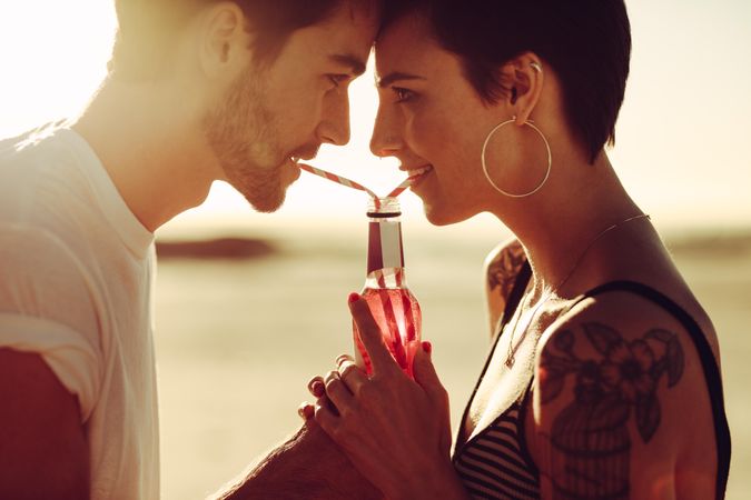 Young man and woman sharing a beverage outdoors