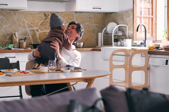Happy father embracing unrecognizable daughter in kitchen