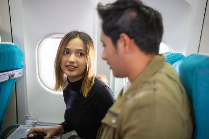 Male and female passengers talking together in airplane