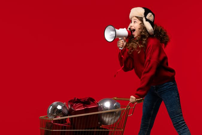 Energetic girl in sweater and fur hat shouts into megaphone