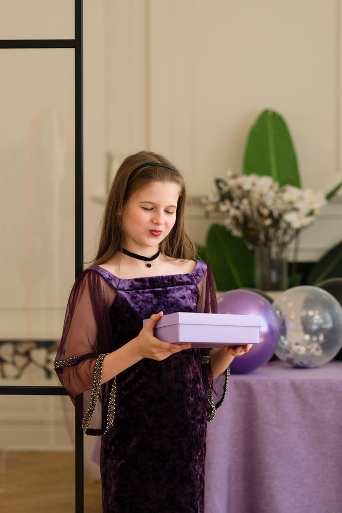 Girl looking at gift box at birthday party.