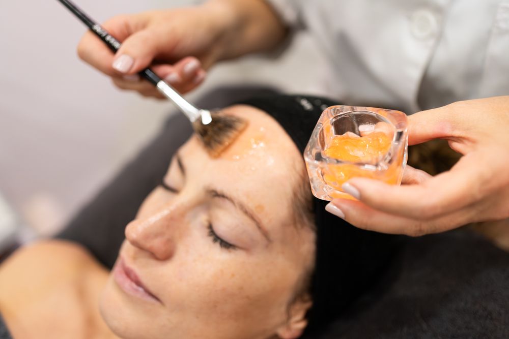 Beautician brushing product on client's forehead