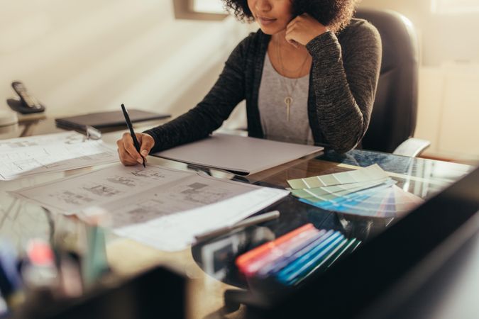 Female architect working on house floor designs at her work desk