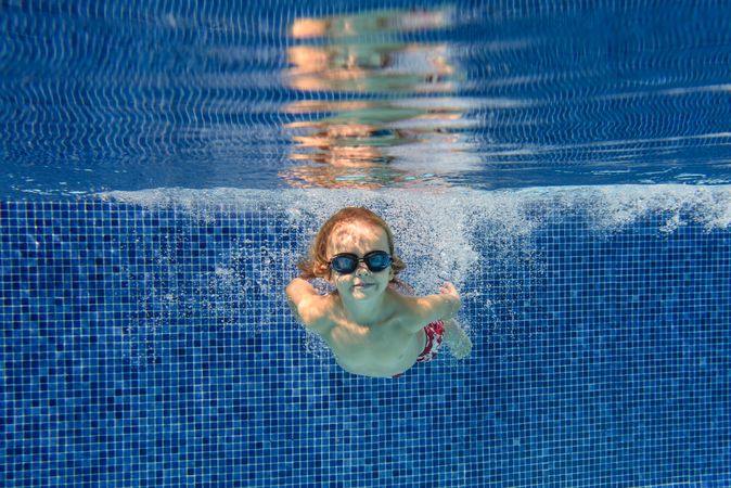 Content boy swimming underwater in pool