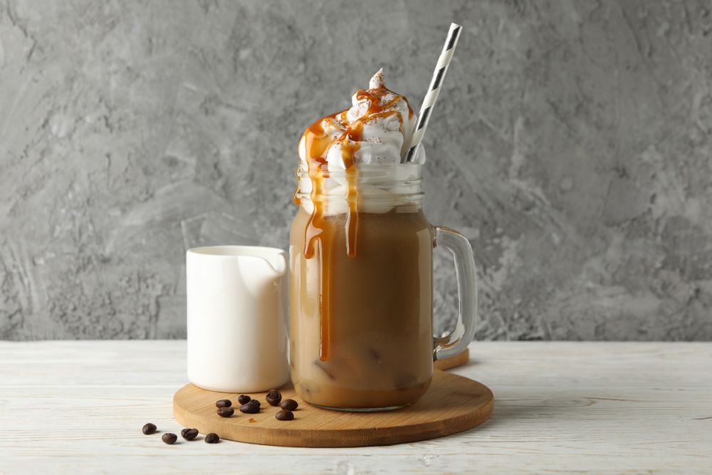 Iced coffee with poured cream on wooden background