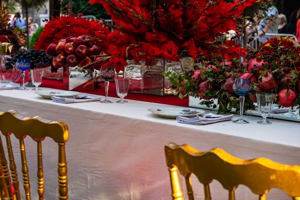 Formal dinner table with red seats and red floral arrangements