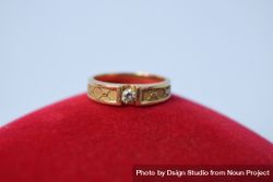 Man's diamond ring resting on red cushion 56Gvrd