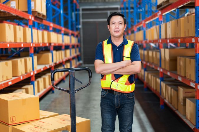 Man working in warehouse with big trolley for boxes