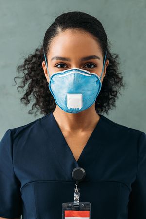 Black female medical professional in dark scrubs and protective face mask