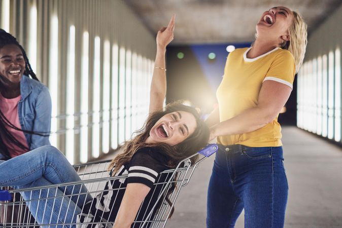 Group of playful friends having fun with shopping cart