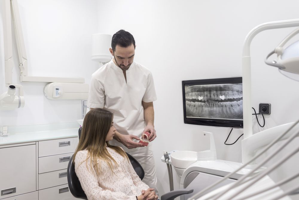 Doctor showing patient how to clean teeth on jaw sample
