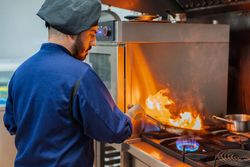 Chef cooking with flame in frying pan