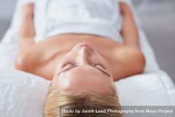Blonde woman with eyes closed lying back and relaxing after treatment beXy2A